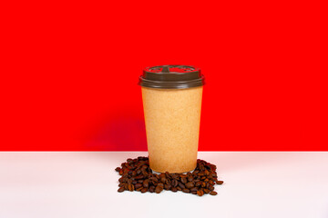 A cup of takeaway coffee and coffee beans on a red, orange background. The concept of a beautiful mug made of kraft paper.
