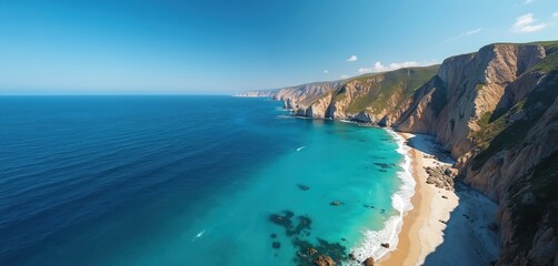 Obraz premium Stunning aerial view of a tropical coastline with sheer cliffs meeting clear turquoise ocean waters and a sandy beach below. Lush green vegetation covers cliff tops under a bright blue sky.
