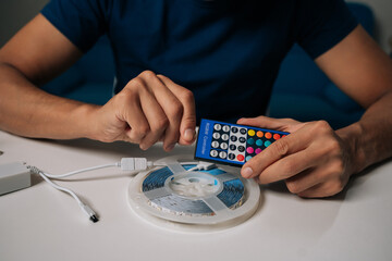 Cropped shot of technician connecting RGB controller to roll of led strip lights, preparing for installation and creating customized lighting solutions for enhanced ambiance and modern interiors.
