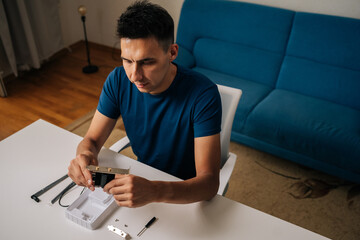 High-angle view of technician male assembling wi-fi module using tools at home office desk, focusing on intricate components and ensuring proper connection. Concept of desktop PC maintenance