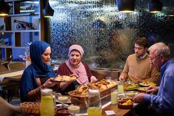 Muslim family enjoying iftar meal in a restaurant with Ramadan decorations during evening hours