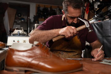 Cobbler at work repairing leather shoe with hammer and awl in a focused old-world workshop