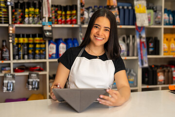 Young woman smiling while holding a tablet in a small business hardware store