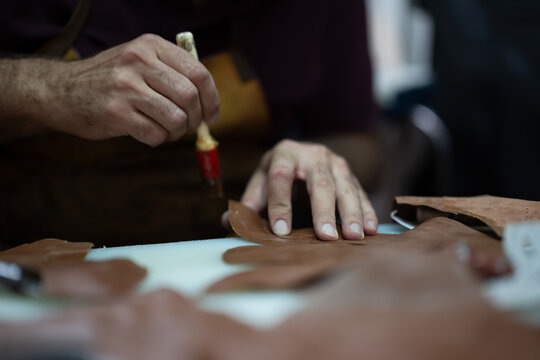 Leather craft in progress: close-up of hands shaping leather pieces with a tool