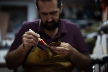 Artisan chocolatier at work, carefully applying glaze to a chocolate piece with a fine brush in a busy workshop
