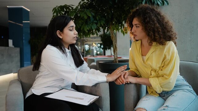 Empathetic Indian psychologist comforting depressed female patient