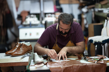 Shoemaker at work in a leather workshop crafting brown dress shoes with precision