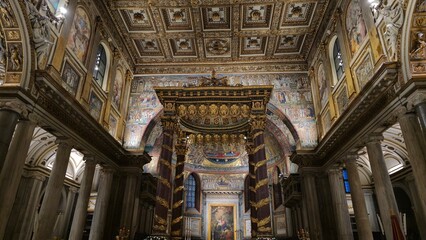 Rome, Italy - 13 January 2025. Baldachin with twisted columns and gold trim beneath coffered ceiling, framed by frescoed walls and marble columns in Saint Mary Major&rsquo;s apse.