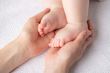 A tender newborn moment shows tiny feet resting in warm, gentle hands, capturing parental love, safety, and new life in a quiet, comforting setting