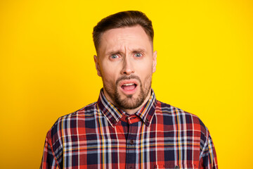 Fototapeta premium Surprised tall handsome man with plaid shirt standing against bright yellow background