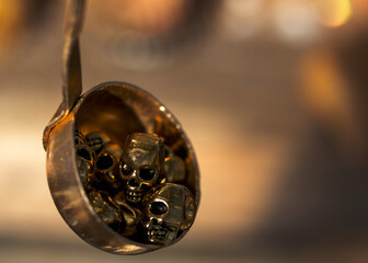 Golden skulls in a metal scoop on a blurred background