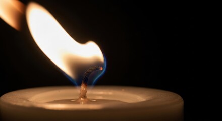 Close-up of a lit candle with blue flame against a black background