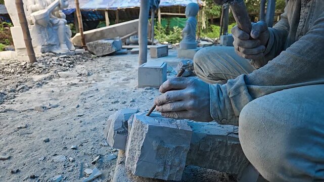 Indian Skilled artisan carefully carves stone using a hammer and chisel, showcasing traditional craftsmanship, sculpture making, and handmade stone art.