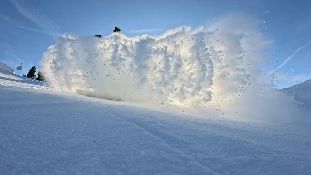 LENS FLARE, LOW ANGLE VIEW, SLOW MOTION: Snowboarder sends a cloud of snow towards camera as he makes a turn while riding through snowpark. Fun snowboarding at ski resort in the snowy Austrian Alps.