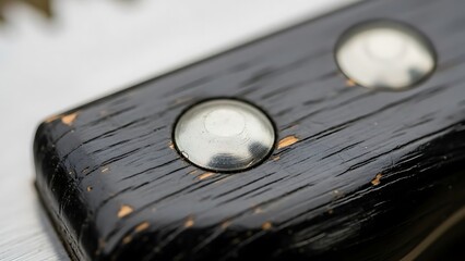 Close-up of a riveted black wooden handle with evident wear and tear