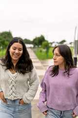Obraz premium Young women friends walking and talking outdoor park
