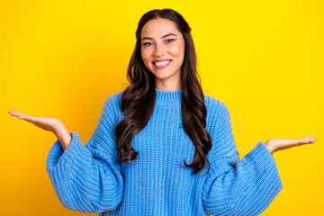 Young mixed race woman smiling wearing blue sweater presenting with open palms against yellow...