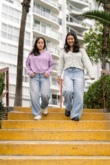 Young women walking downstairs outdoors talking looking happy