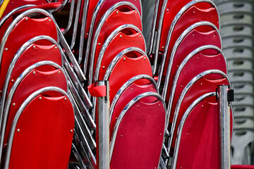 Red velvet chairs with chrome frames organized and stacked for storage, event preparation concept.