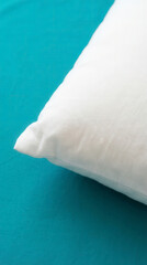 Close up of a white pillow resting on a vibrant teal blue textured surface