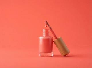 Coral nail polish bottle with brush dripping a drop of lacquer on a solid coral background