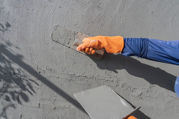 Hand worker plastering with holding trowel handle wet grey cement mix Plaster wall concrete Background well free space for text presentation construction house site
