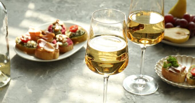 Delicious bruschette, wine and fruits on table. Camera zooming out