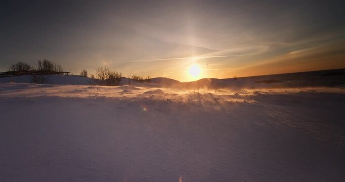 Frozen landscape of snow covered field after a blizzard, ice desert, winter wonderland, wind blows snowflakes, morning sunlight, polar sunrise 4K cinematic video
