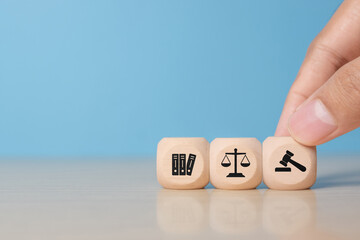 Wooden blocks showcase icons of law, justice, and finance. A finger selects a block, symbolizing choice in legal decisions and fairness. Represents legal system, court, and financial regulations.