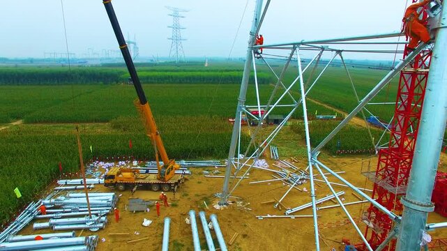 High Voltage Tower Construction Site with Crane and Workers