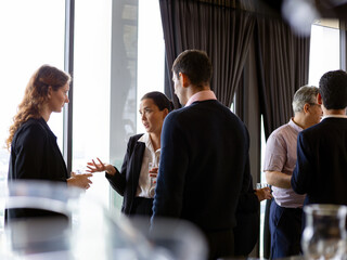 Business professionals having conversations and networking during a corporate event in a modern office setting, highlighting communication, teamwork, and professional interaction
