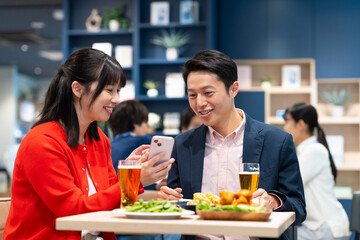 飲食店でスマホを見るミドルのカップル