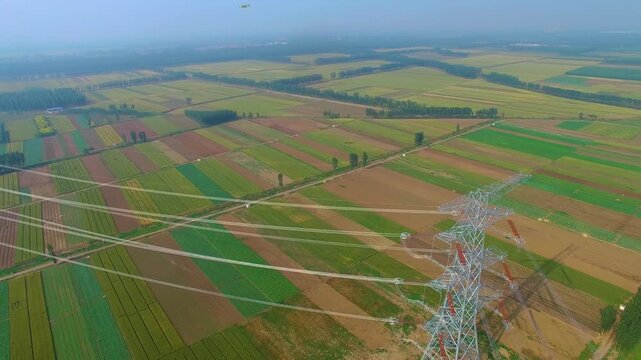 High Voltage Power Tower Over Agricultural Farmland - Aerial View