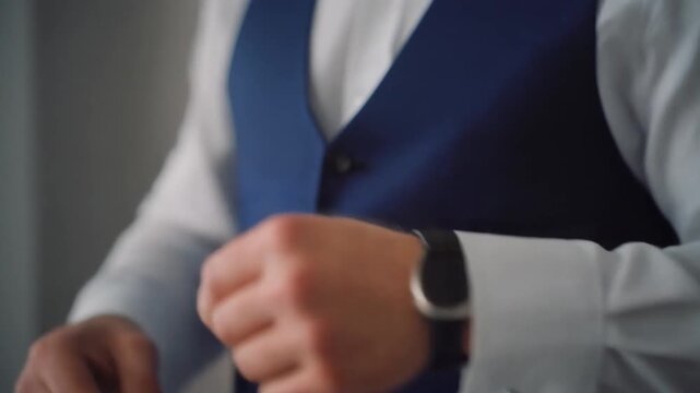 closeup of man adjusting cufflinks with elegant blue vest