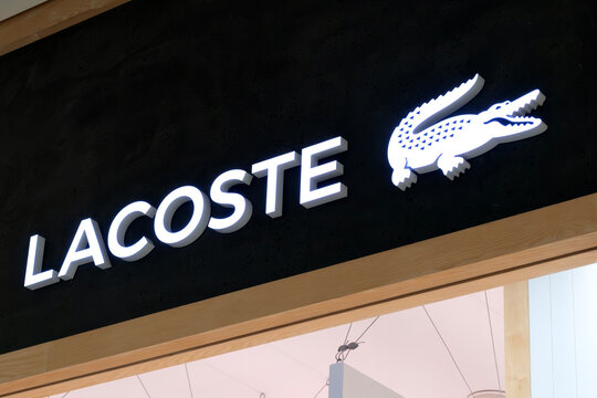 London, UK - December 18 2025: Illustrative editorial Lacoste logo illuminated on fashion retail store signage with crocodile emblem