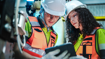 Diverse engineering team working with a white industrial robotic arm. A woman with curly hair in...