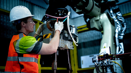 An engineer programs or repairs a high-tech industrial robot. This smart factory uses AI-driven automation for advanced manufacturing or microchip production.