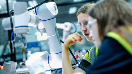 Two female engineers represent the future of work, using AI and robotics to optimize production. They are innovating for the high tech manufacturing supply chain.