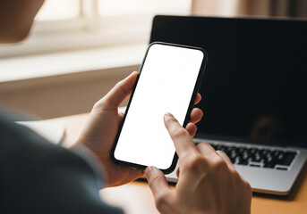 Overhead view of hands holding a smartphone with a blank screen, placed on a wooden table next to a camera and notebook