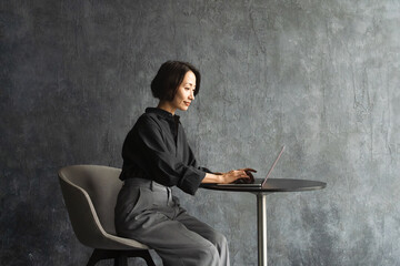 テーブルでラップトップを操作する女性　ライフスタイルイメージ