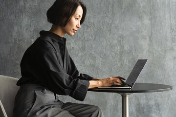 テーブルでラップトップを操作する女性　ライフスタイルイメージ