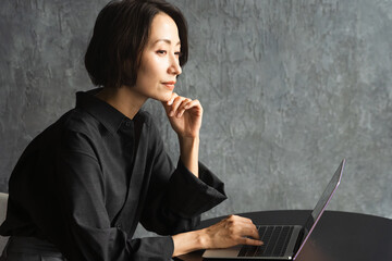 テーブルでラップトップを操作する女性　ライフスタイルイメージ