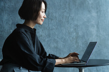 テーブルでラップトップを操作する女性　ライフスタイルイメージ