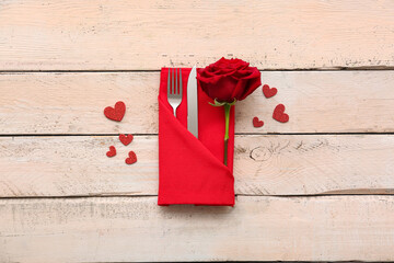 Table setting for Valentine's Day with cutlery, decorative hearts and rose flower on wooden...
