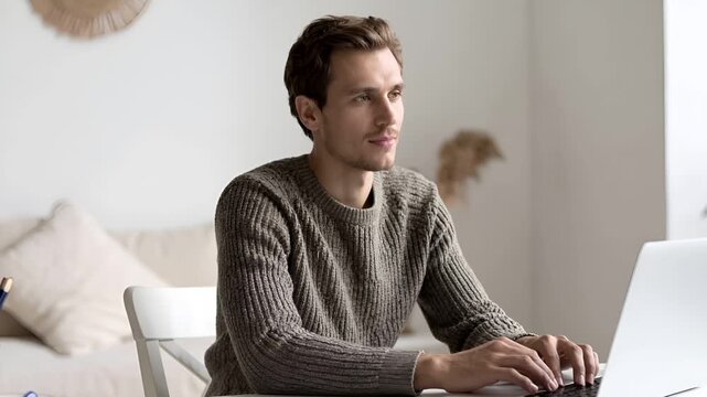 明るくミニマルな自宅空間で、ノートパソコンを使って仕事をする男性