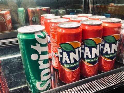 rows of chilled sprite and fanta soda cans in a refrigerated display