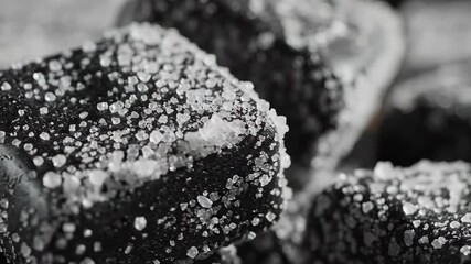 A captivating closeup black and white macro shot revealing the intricate texture of a delicious baked treat generously coated with sparkling sugar crystals highlighting its tempting granular surface .