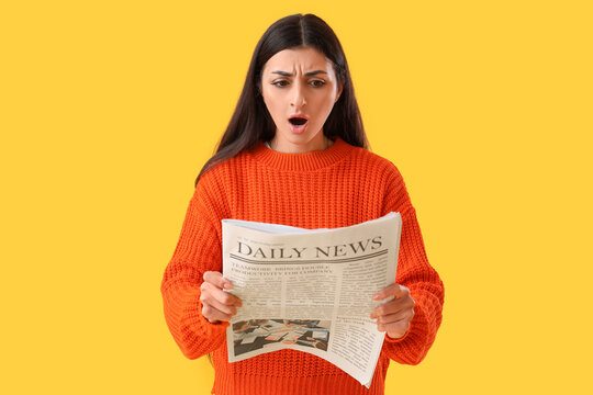 Shocked young woman reading newspaper on yellow background. Search concept - Powered by Adobe