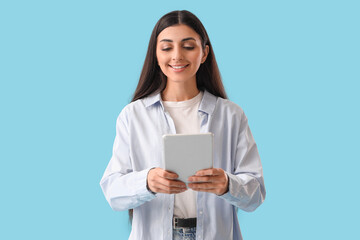 Young woman with tablet computer on blue background. Search concept