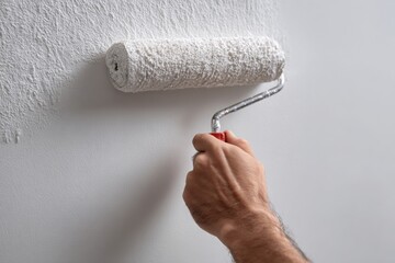 Close-up of hand painting wall with roller
